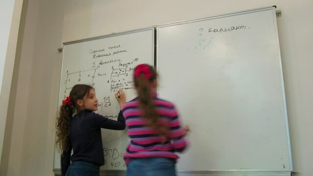 Pair of girls writes schema and formulas on whiteboard. Timelapse