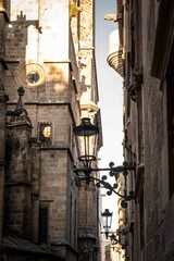 calle de la zona antigua de una ciudad europea, Barcelona, donde se ve una farola y una iglesia