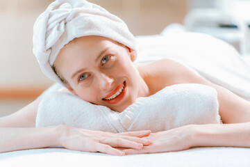 A beautiful young woman lies on a spa bed, her body relaxed and at peace. Pretty caucasian girl...