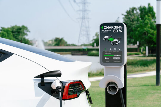 Electric vehicle or EV car recharge battery at charging station connected to power grid tower electrical industrial facility as electrical industry for eco friendly vehicle utilization. Expedient