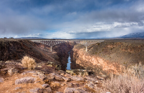Rio Grande Gorge Bridge showing full span of bridge, Rio Grande far below, and storm clouds beyond