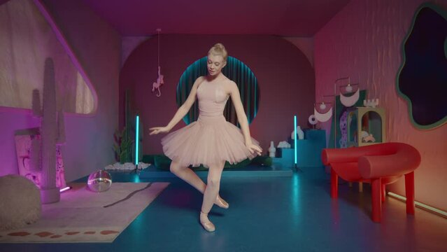 Zoom in shot of graceful ballerina in tutu dancing on pointe in studio with trendy designed interior and neon light