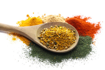 Curry in wooden spoon with cayenne pepper ground, ginger, dill chopped and turmeric powder isolated...