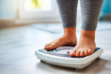 Close up of overweight woman standing on bathroom scale. With the help of a fitness trainer, she will try to get rid of excess weight through exercise. - Powered by Adobe