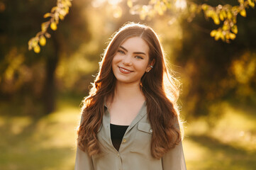 Close up shot of a young cheerful woman with long blonde hair outdoors in park on a sunny day.