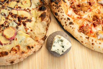 Dos pizzas al horno a detalle en medio una piedra con queso azul