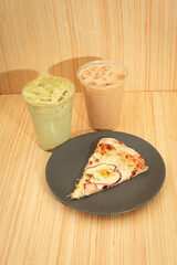 Rebanada de pizza de manzana en un plato gris con jugo verde y café frio en un fondo de madera imagen vertical