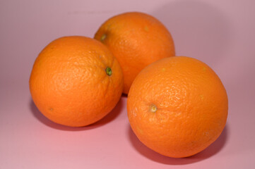 three juicy oranges on a pink background studio shooting 4