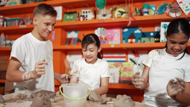 Multicultural Happy Student Playing By Throw Clay While Modeling Cup In Pottery Class. Caucasian High School Girl Pointing At Boy While Smiling Smart Boy Laughing At Art Lesson. Education. Edification