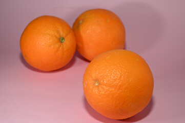 three juicy oranges on a pink background studio shooting 2