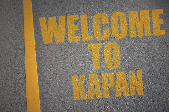 asphalt road with text welcome to Kapan near yellow line.