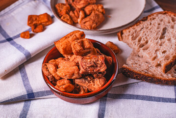 Heap of domestic salty fried pork greaves. Fatty junk food. Pork greaves on the kitchen board.