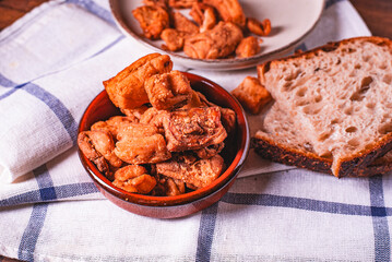 Heap of domestic salty fried pork greaves. Fatty junk food. Pork greaves on the kitchen board.
