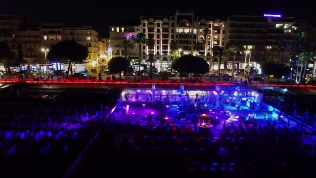 Night club on beach near Croisette boulevard with crowd of people and traffic