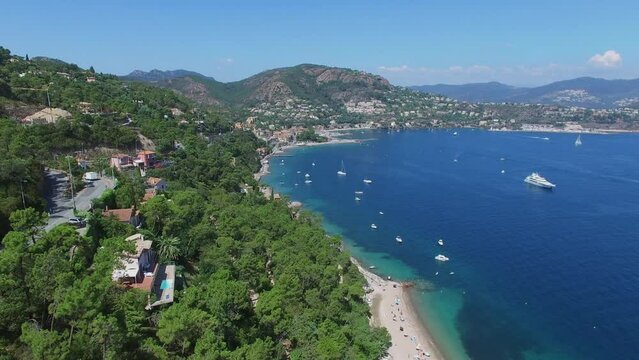 Traffic on mountain road and vessels sail by sea bay near coastal town
