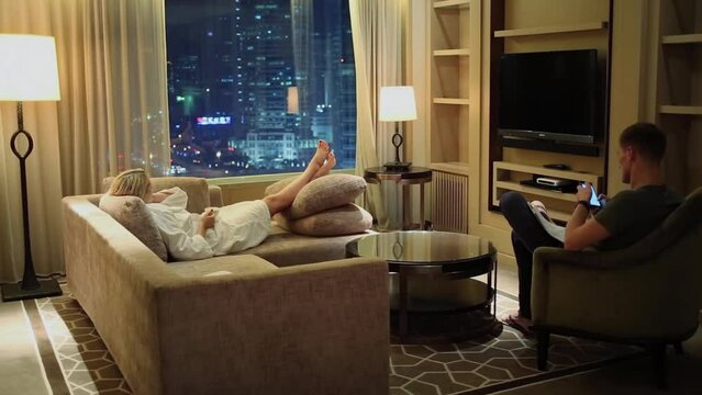 Couple get rest in sitting room near window with night city view