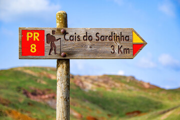 Wooden signpost pointing at the Cais do Sardinha (sardine pier) on the Ponta de São Lourenço (tip of St Lawrence) at the easternmost point of Madeira island (Portugal) in the Atlantic Ocean