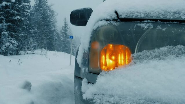 A vehicle hazard blinking as it sits stationary during an intense snowstorm, highlighting the dangers of winter driving, a close-up view.