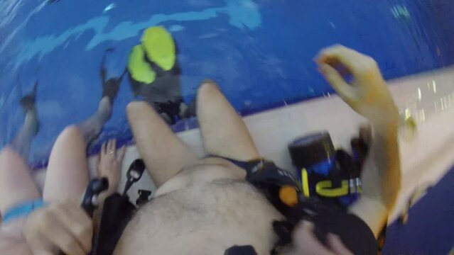 Man dresses scuba before diving in pool, FPV, top view