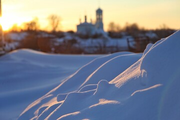 Evening winter photo of snow drifts and drifts against the backdrop of the setting sun and a...