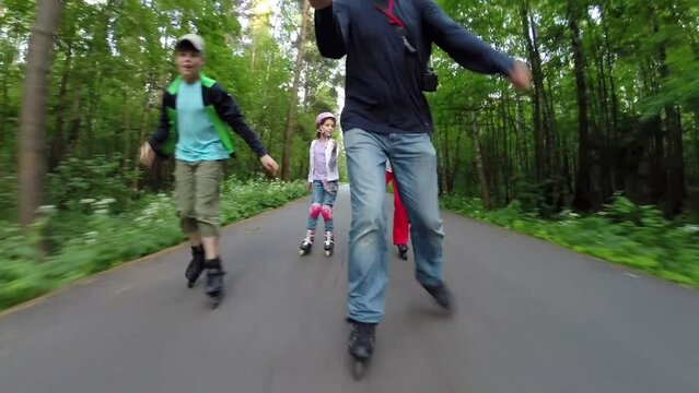 Man, woman and two children roller skate in green park, man makes selfie