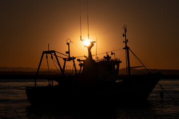 Contraluz dorado de un barco pesquero al atardecer en el puerto de Isla Cristina, España.