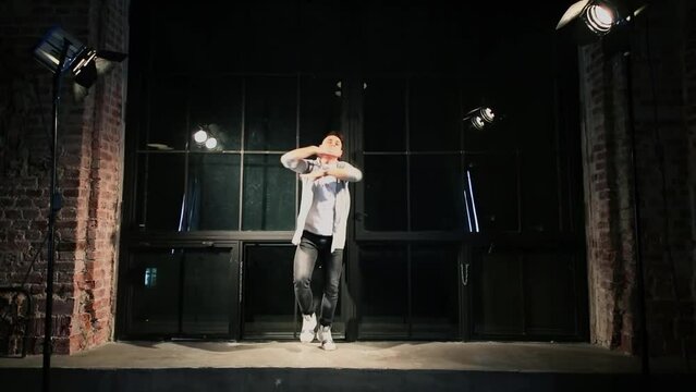 Young man wearing t-shirt dances in modern style