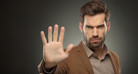 Portrait of a handsome young man making stop gesture on grey background