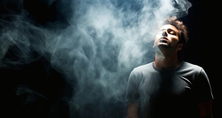 Young man smoking a cigarette on a black background. Smoke from a vape. - obrazy, fototapety, plakaty