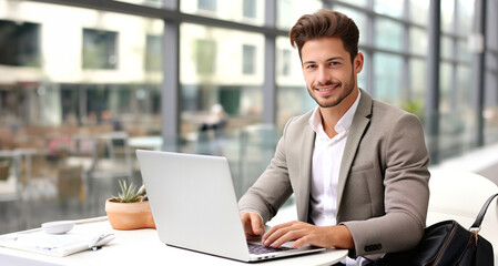 Fototapeta premium Handsome young businessman working with laptop in office. Space for text