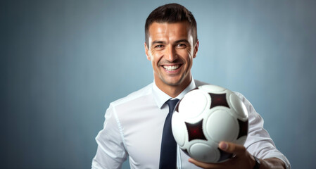 Portrait of a young businessman holding a soccer ball on grey background