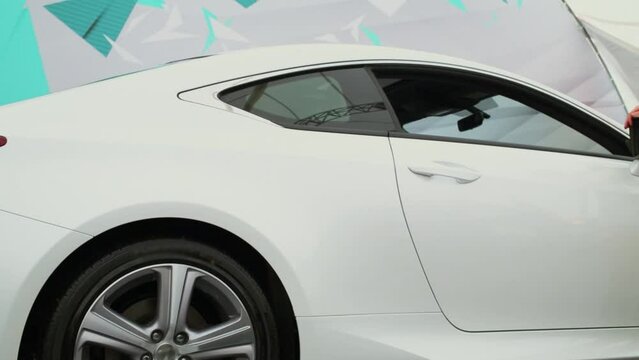 Woman in summer dress walks near white car during exhibition