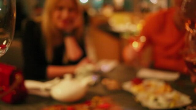 People clinks by four glasses with white vine at restaurant