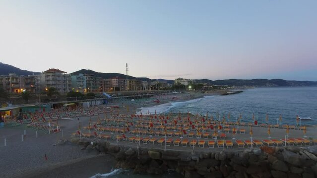 Loano, Italy, City buildings and Marina beach with sunbeds and parasols