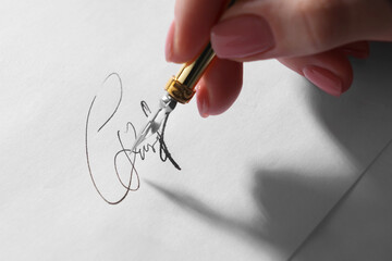 Woman signing on sheet of paper with fountain pen, closeup
