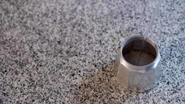 Llenado de agua purificada para preparar cafe de cafetera italiana en el desayuno cafe&iacute;na