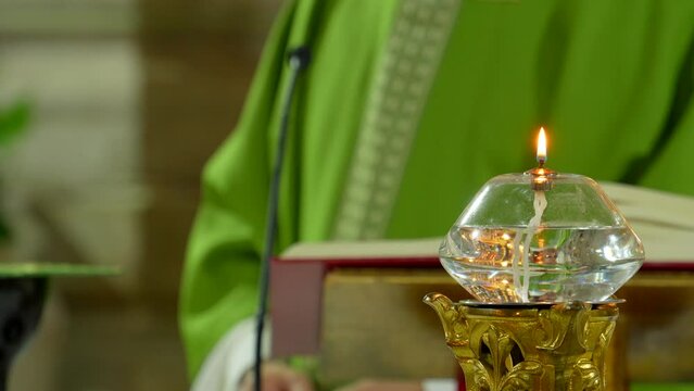 sacerdote cat&oacute;lico cristiano celebrando misa solemne oficio misal romano apost&oacute;lico vestimenta verde y vela en el altar candela