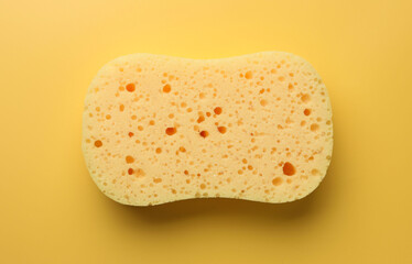 New sponge on yellow background, top view