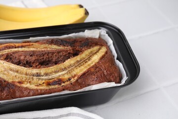 Delicious banana bread and fresh fruits on white tiled table, closeup