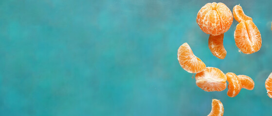 Falling peeled tangerines on light blue background with space for text