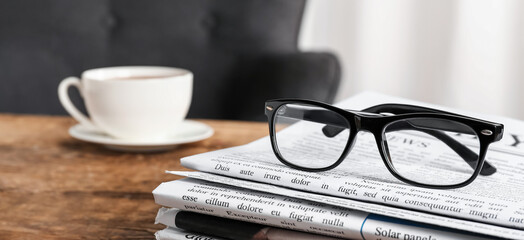 Many newspapers with eyeglasses on table in office, closeup