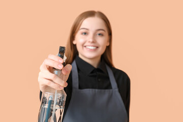 Female hairdresser with spray on beige background, closeup