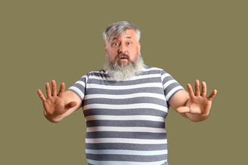 Afraid mature man on green background