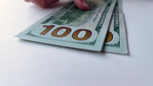 4K video closeup. Female hands count paper American green banknotes of 100 USD on white background. One hundred dollars US. Concept of accounting, immigration, getting paid, travel, tourism. Salary