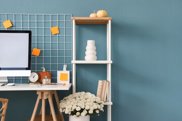 Comfortable workplace with modern computer, chrysanthemum flowers and pumpkins at home