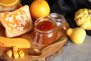 Jar and toast with sweet pumpkin jam on grey table
