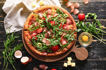 Board of delicious pizza with tomatoes and arugula on black wooden background