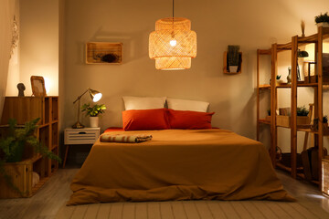 Interior of cozy bedroom with shelf units and glowing lamps at night