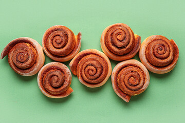 Tasty cinnamon rolls on green background
