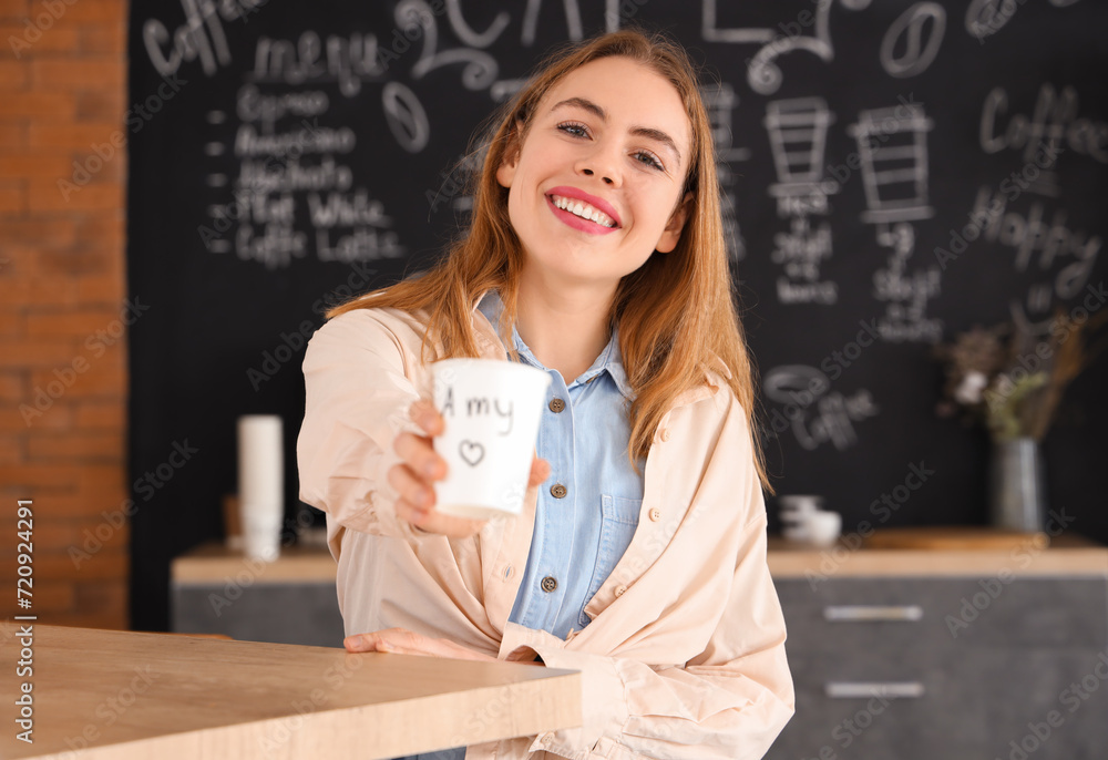 Sticker Young woman with cup at table in coffee shop